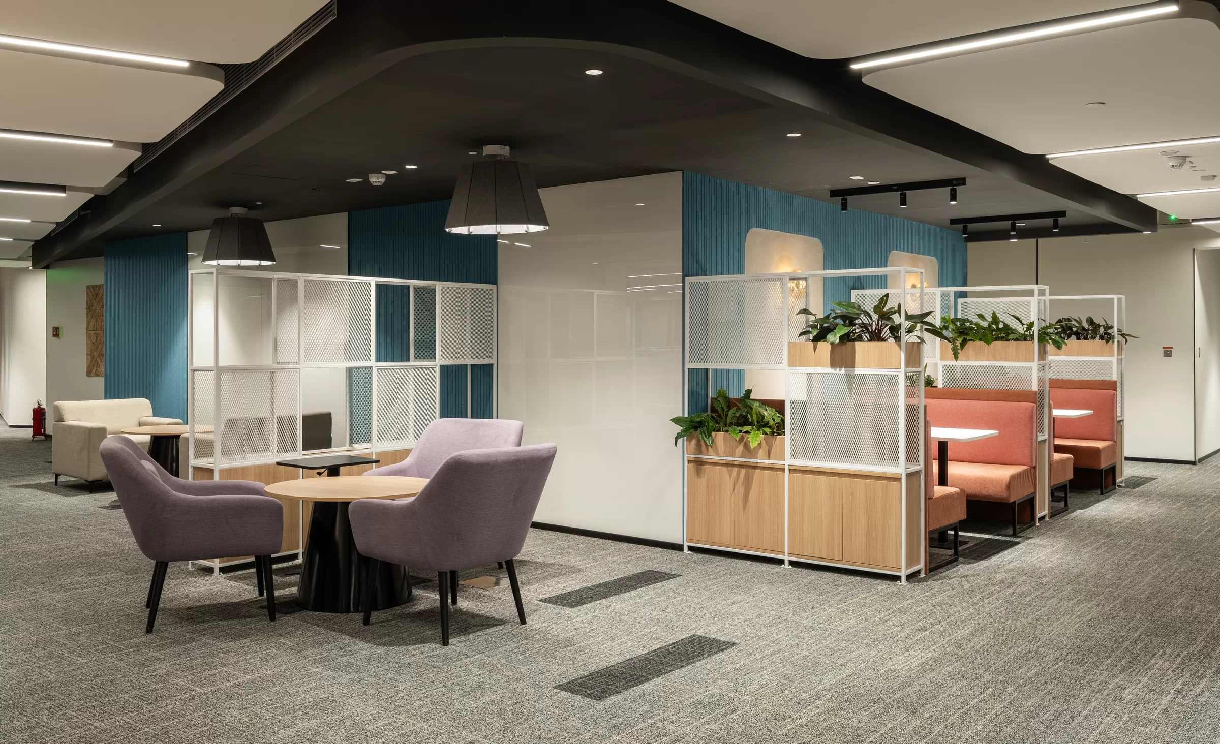 Contemporary office lounge with upholstered chairs, booths and planted dividers