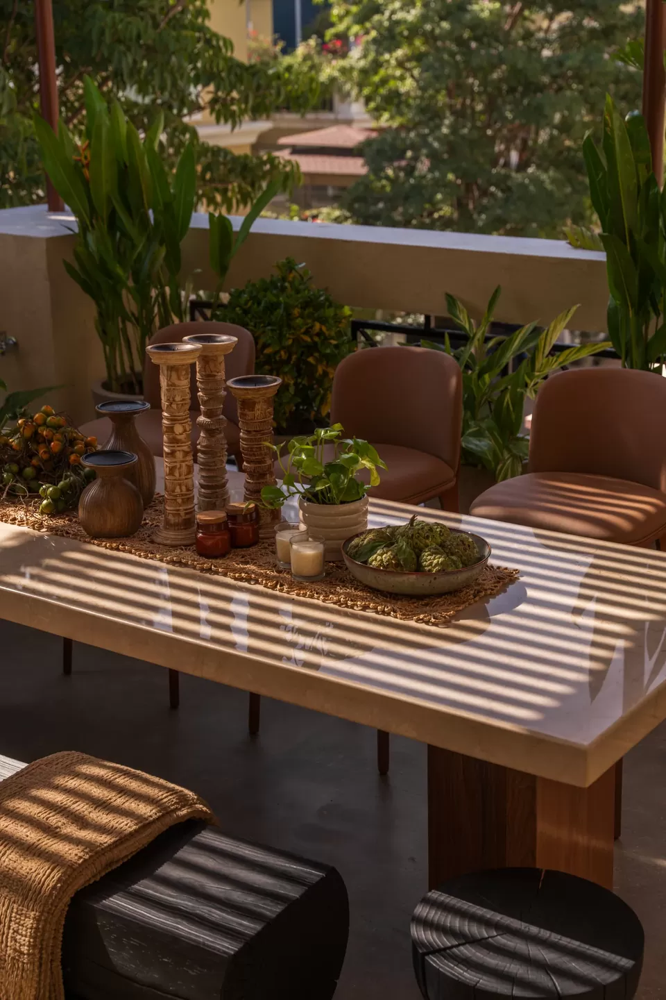 Terrace dining table and seating beneath striped sunlight from a timber pergola