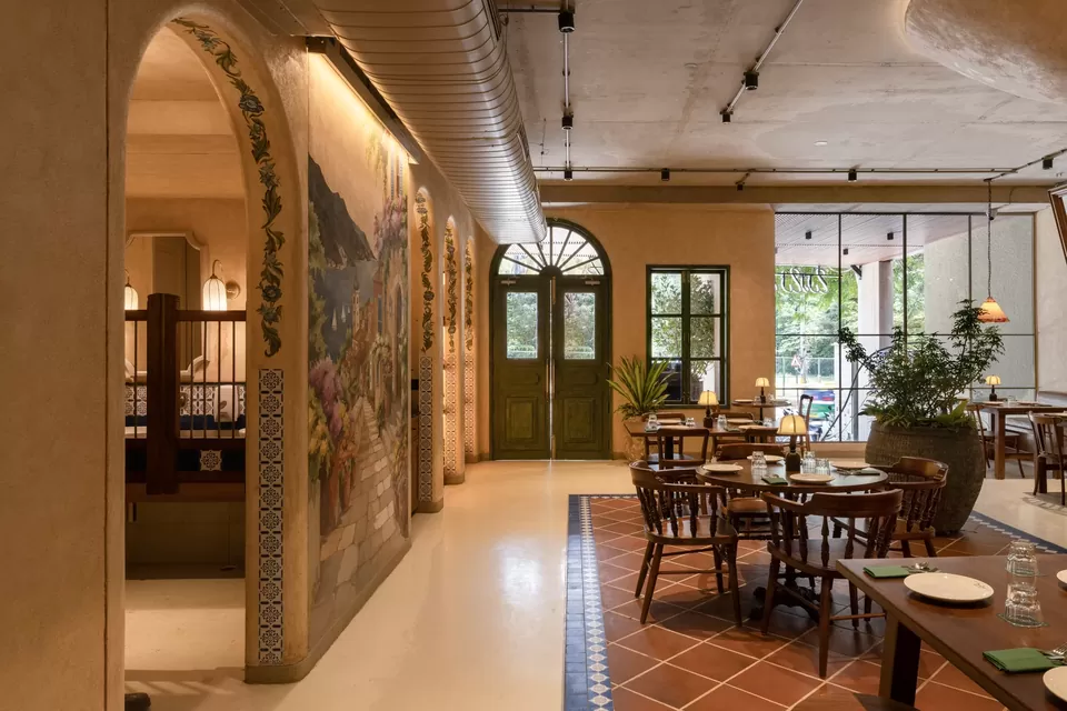 Terracotta-toned restaurant dining room framed by arches and green doors